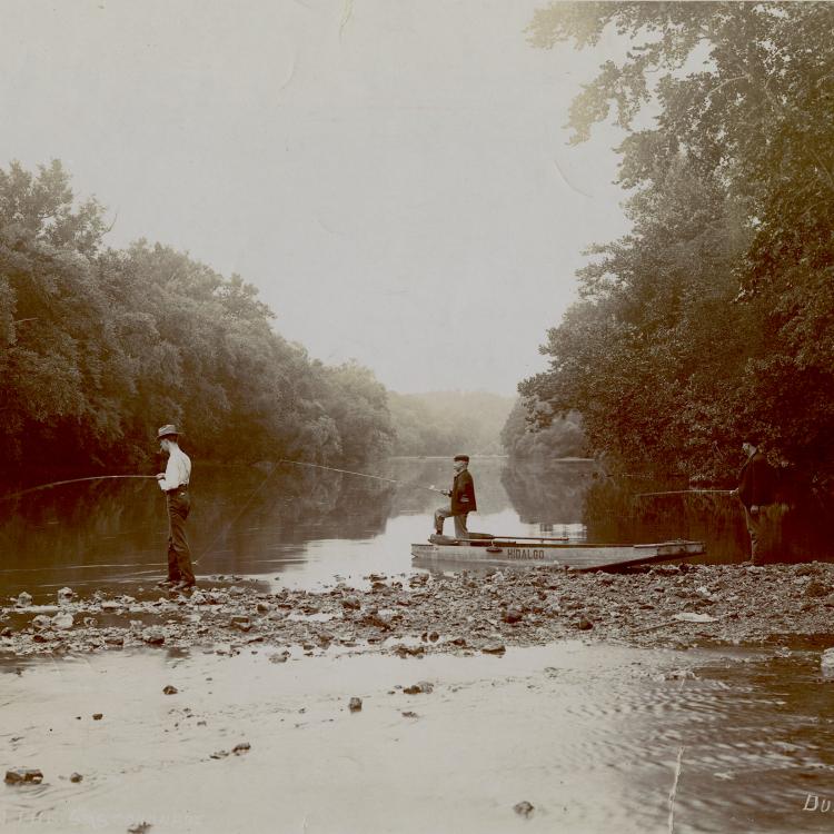 Three men fishing on an Ozarks river; one stands in a johnboat named Hildalgo. [State Historical Society of Missouri, State of Missouri Collection, P0018]