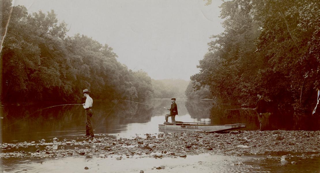 Three men fishing on an Ozarks river; one stands in a johnboat named Hildalgo. [State Historical Society of Missouri, State of Missouri Collection, P0018]